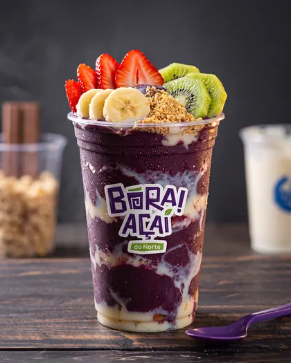Copo de açaí com frutas sobre balcão de madeira