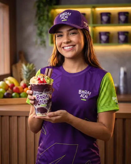 Atendente sorrindo segurando um copo de açaí